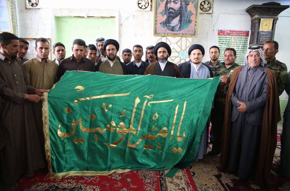 تقديم راية أمير المؤمنين (ع) إلى عائلة الشهيد شيخ المجاهدين في فرقة الإمام علي (ع) التابعة للعتبة العلوية